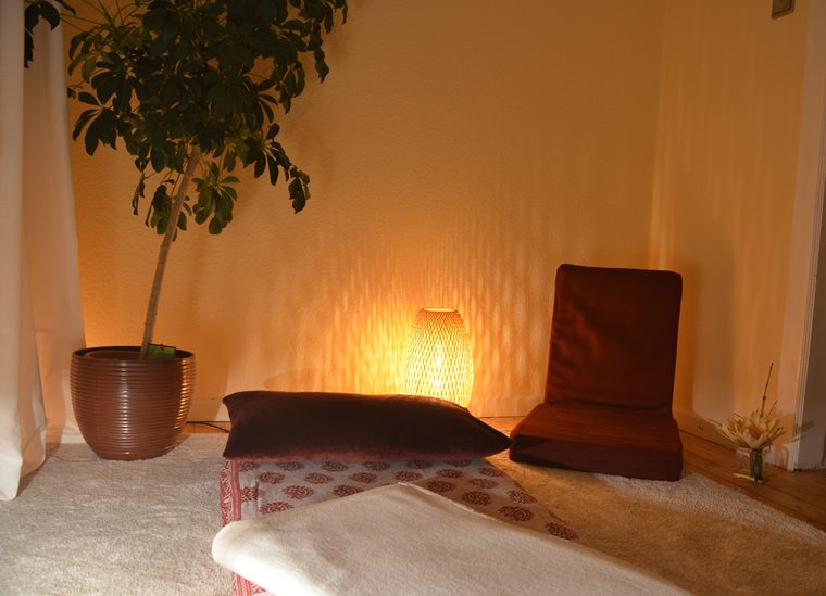 Behandlungsraum mit Pflanze, warmem Licht und Sitzkissen am Boden